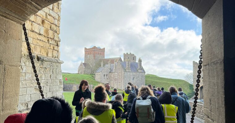 Children walking through an arched stone walkway at Dover Castle during the Schools Climate ExChange event.