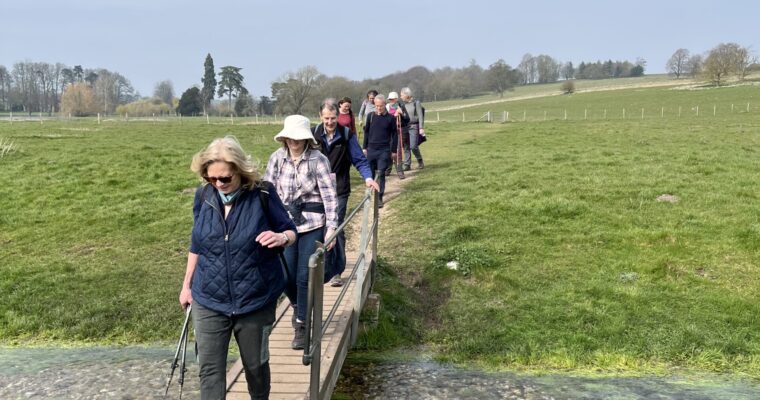 Members of Are We There Yet Rambling walking group crossing a small stream on a wooden bridge